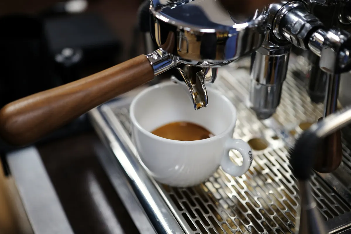 Espresso mit Crema in einer weißen Tasse unter dem Siebträger