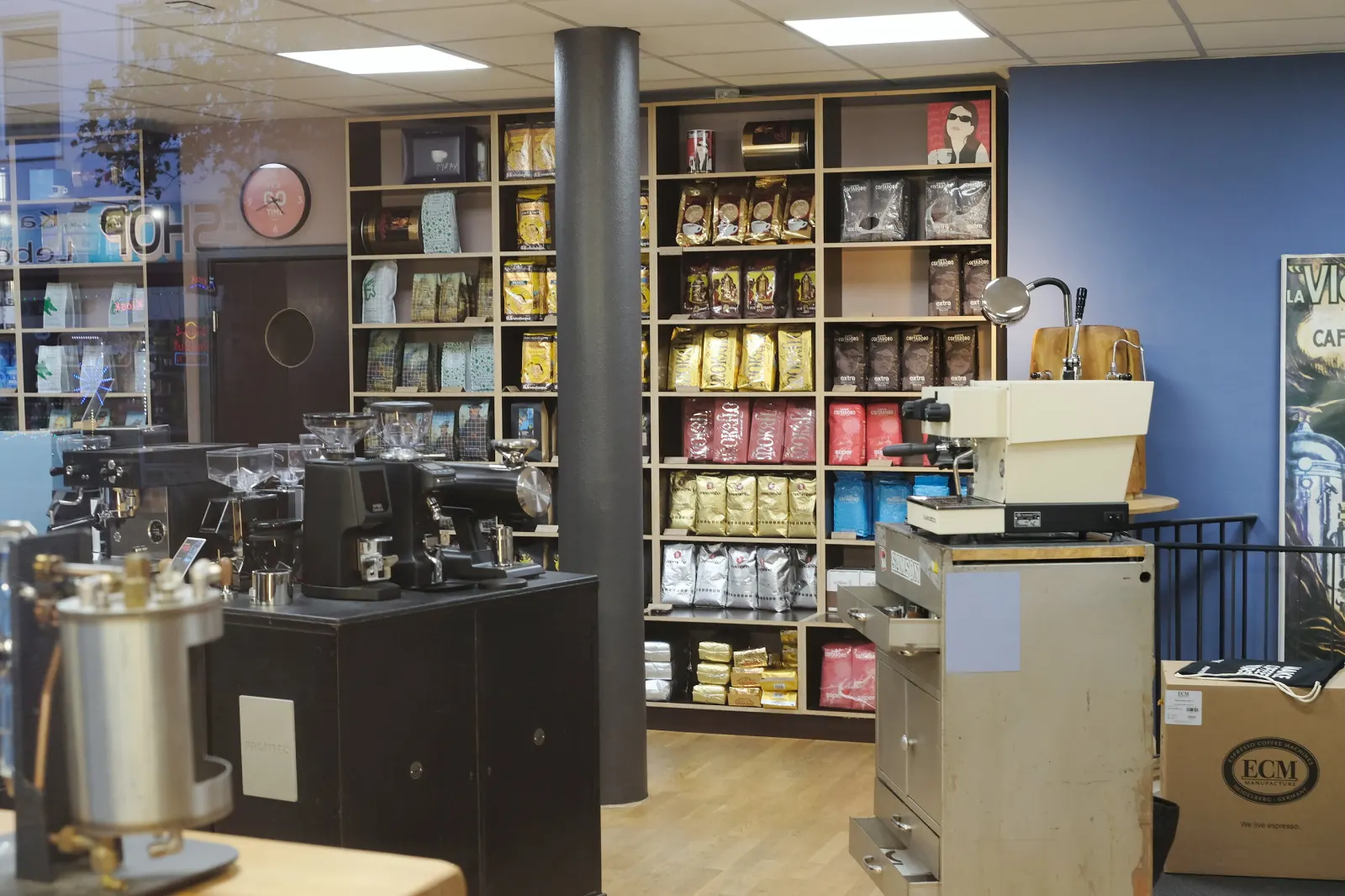 Kaffeeregal mit vielen Sorten und Siebträgermaschinen im Laden