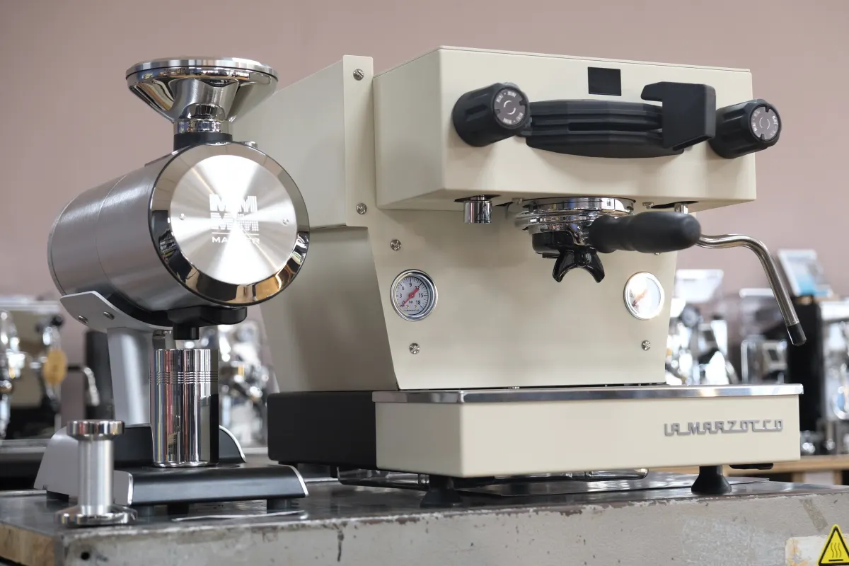 Espressomühle neben einer cremefarbenen La Marzocco