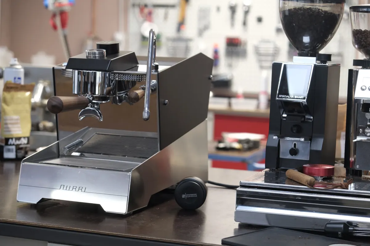 Siebträgermaschine von Nurri in Edelstahl neben einer Espressomühle